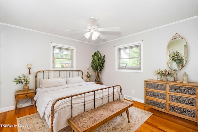 bedroom with crown molding, wood finished floors, baseboards, and ceiling fan