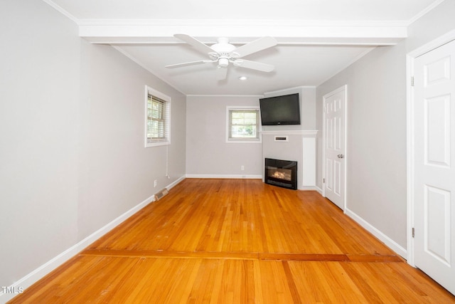 unfurnished living room featuring a glass covered fireplace, light wood-type flooring, baseboards, ornamental molding, and ceiling fan