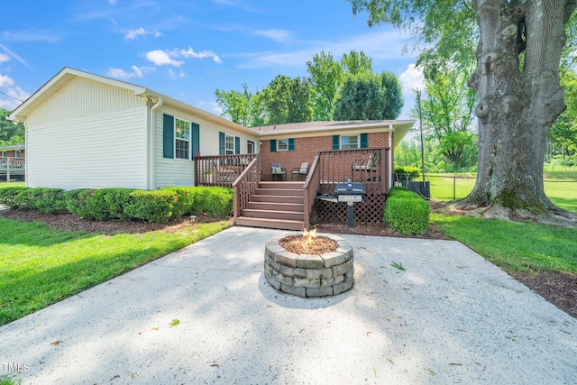 rear view of property featuring a fire pit, a wooden deck, fence, and a patio