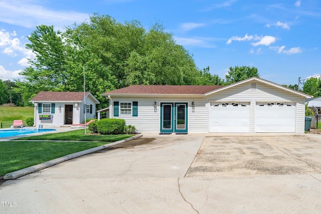 ranch-style house featuring a garage, an outbuilding, a front yard, and concrete driveway