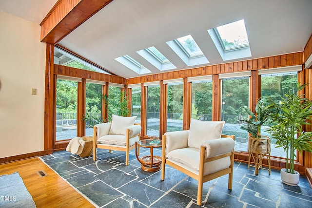sunroom with a skylight, lofted ceiling, healthy amount of natural light, baseboards, and wood finished floors