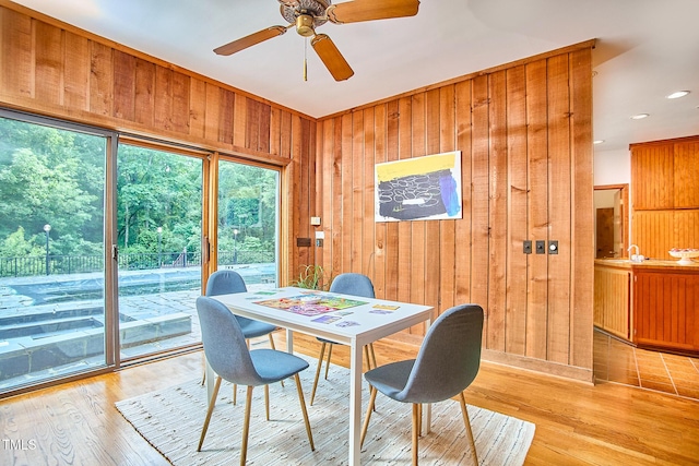 dining room featuring wooden walls, a ceiling fan, light wood-style flooring, and recessed lighting
