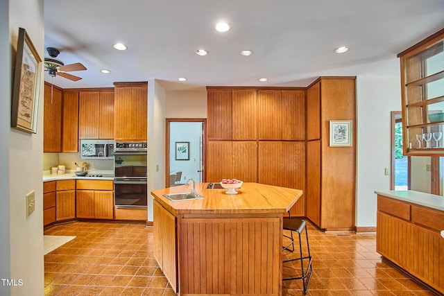 kitchen with black appliances, a sink, recessed lighting, ceiling fan, and a center island with sink