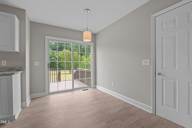 114 Lynnville Ct, Lillington, NC 27546 - unfurnished dining area featuring light wood-type flooring, baseboards, and a textured ceiling
