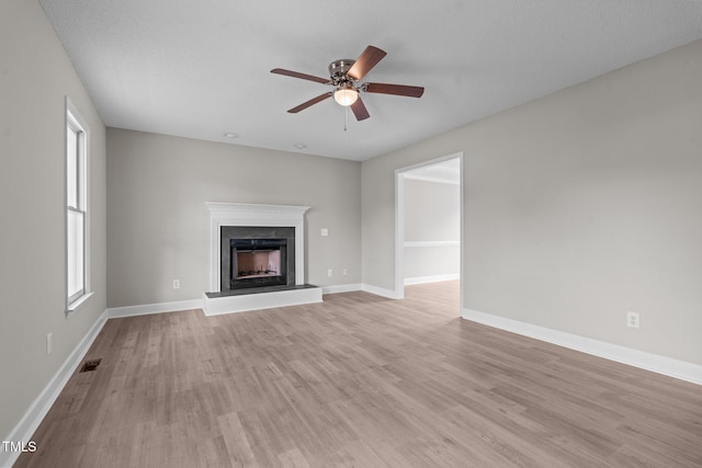 114 Lynnville Ct, Lillington, NC 27546 - unfurnished living room featuring a fireplace with raised hearth, light wood-style floors, a ceiling fan, and baseboards