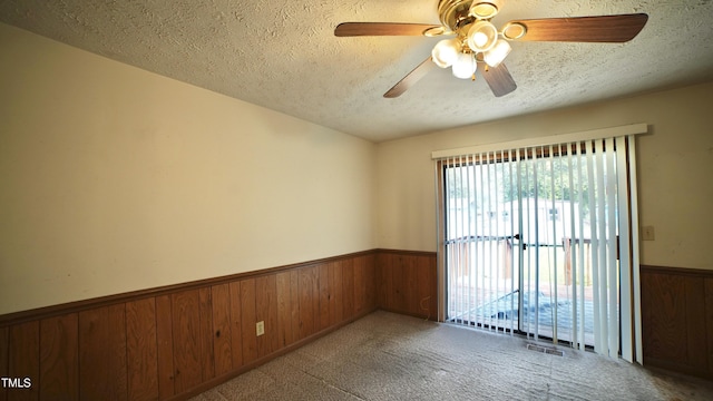 2121 Lombardy Dr, Fayetteville, NC 28304 - empty room featuring wooden walls, wainscoting, a textured ceiling, carpet floors, and a ceiling fan