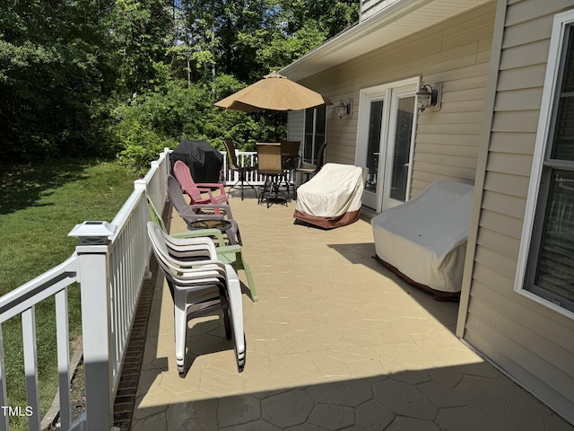 wooden terrace with outdoor dining space, view of wooded area, and area for grilling