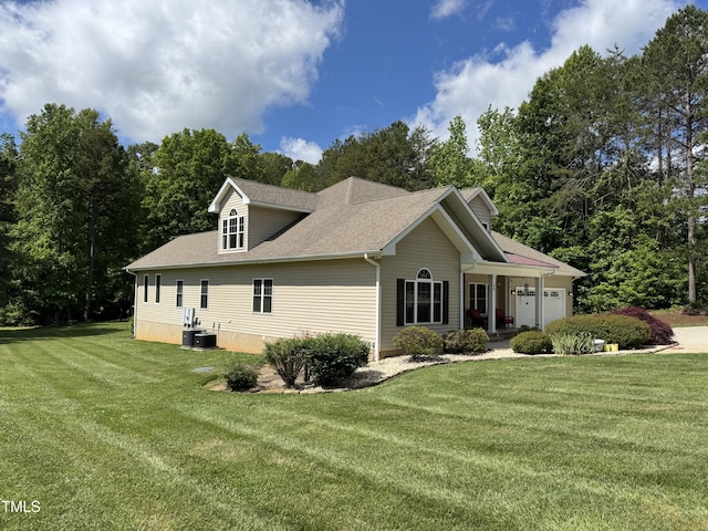 view of side of home featuring a lawn, a garage, and roof with shingles