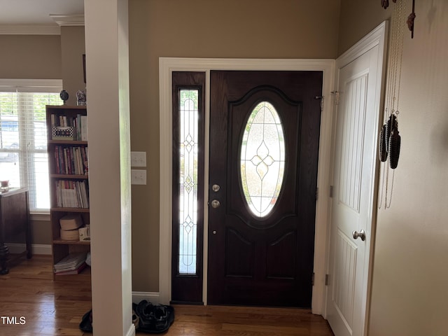 entrance foyer featuring ornamental molding, wood finished floors, and baseboards