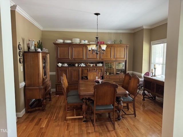 dining area with light wood-style floors, a chandelier, and ornamental molding