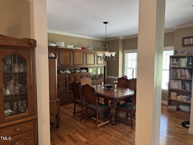 dining room with a chandelier, wood finished floors, and ornamental molding