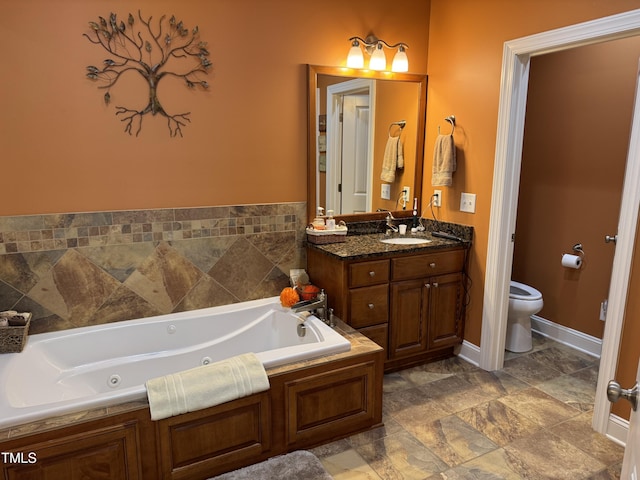 bathroom with toilet, a tub with jets, and vanity