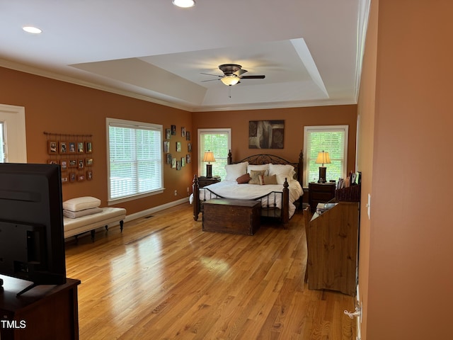 bedroom with a raised ceiling, light wood-type flooring, ornamental molding, recessed lighting, and baseboards