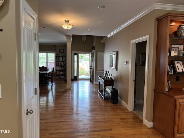 corridor featuring ornamental molding, light wood finished floors, baseboards, and ornate columns