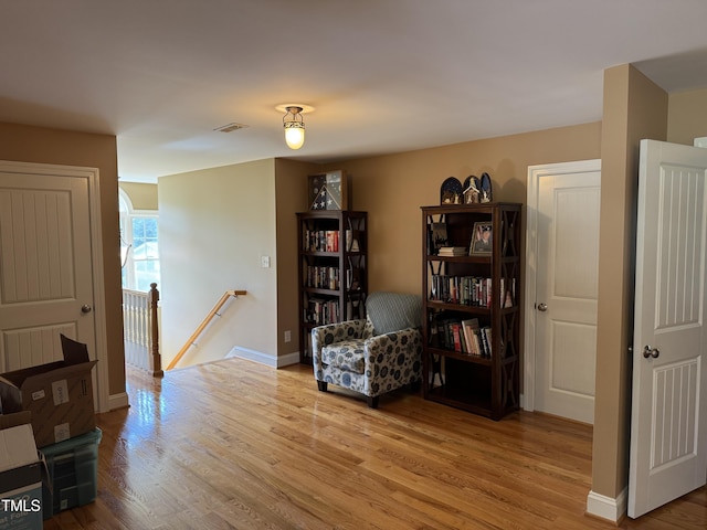 living area featuring an upstairs landing, wood finished floors, and baseboards