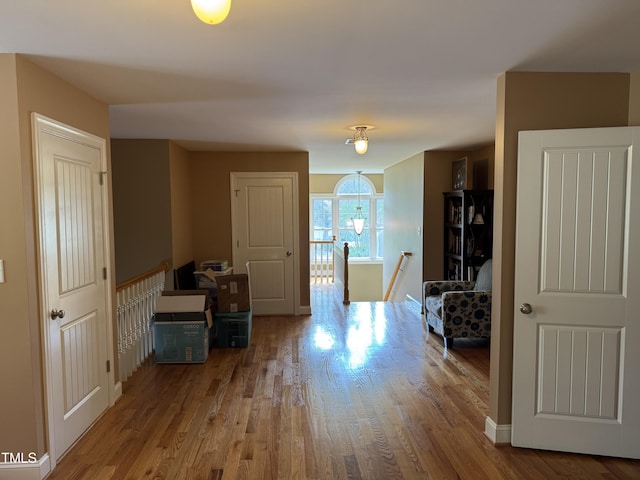 hallway featuring an upstairs landing, wood finished floors, and baseboards