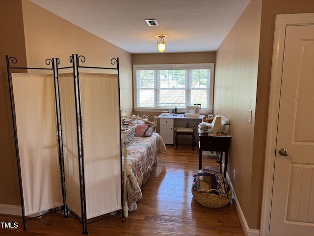 bedroom featuring wood finished floors and an office area