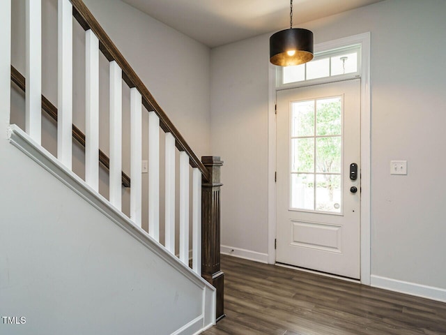 foyer entrance featuring baseboards, wood finished floors, and stairs