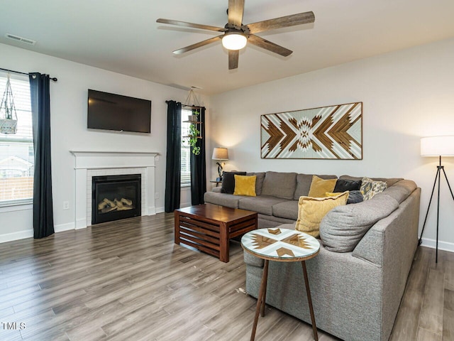 living room featuring a ceiling fan, wood finished floors, healthy amount of natural light, and baseboards