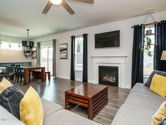 living room with ceiling fan, wood finished floors, a fireplace, and baseboards