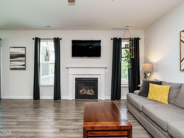 living room featuring wood finished floors, a tile fireplace, and baseboards