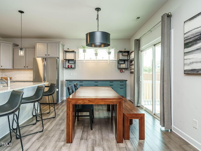 dining area with healthy amount of natural light, light wood-type flooring, and baseboards