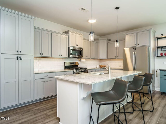 kitchen with stainless steel appliances, a sink, dark wood-type flooring, and decorative backsplash