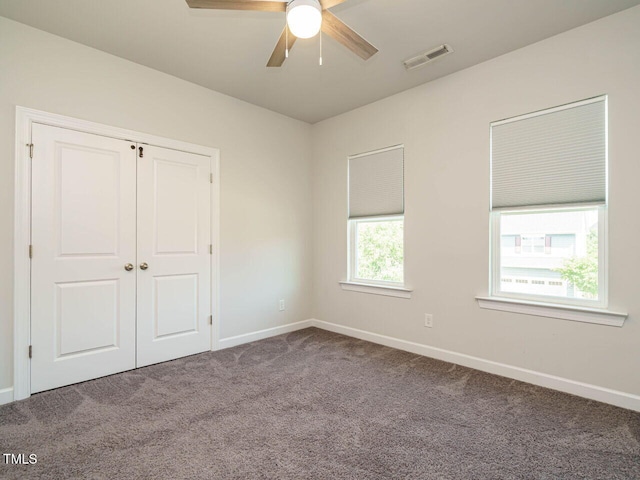 unfurnished bedroom with carpet flooring, baseboards, a closet, and a ceiling fan