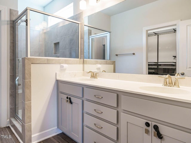 bathroom featuring a stall shower, double vanity, and wood finished floors