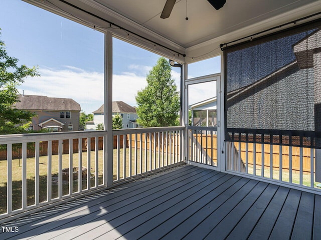 wooden terrace featuring a ceiling fan, a residential view, and a sunroom