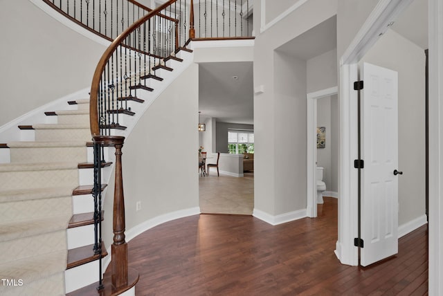 entrance foyer featuring wood finished floors, a high ceiling, stairs, and baseboards