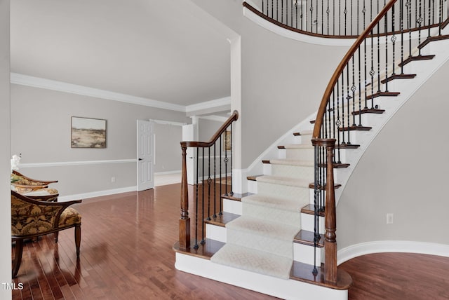 stairs with wood finished floors, crown molding, and baseboards