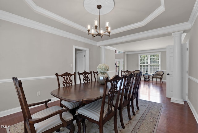 dining space with ornate columns, wood finished floors, a raised ceiling, baseboards, and crown molding