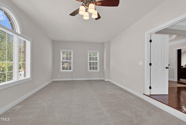 spare room featuring light carpet, ceiling fan, and baseboards
