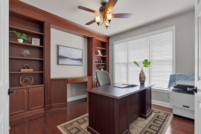 office with ceiling fan, dark wood-type flooring, baseboards, and built in shelves