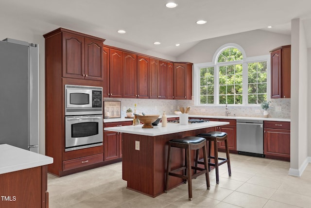 kitchen with appliances with stainless steel finishes, light countertops, backsplash, vaulted ceiling, and recessed lighting
