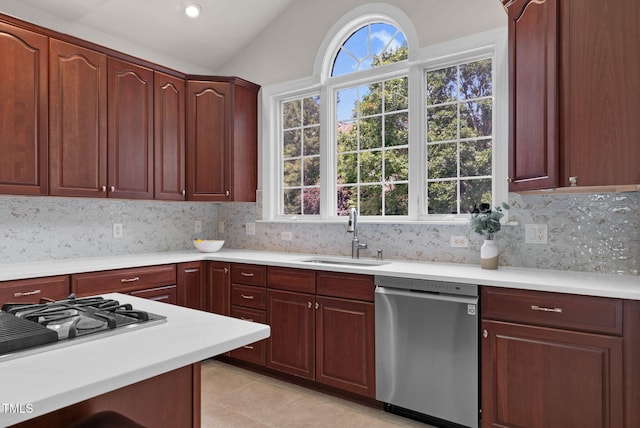 kitchen with stainless steel dishwasher, a sink, lofted ceiling, light countertops, and plenty of natural light