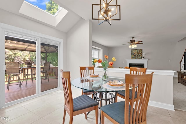 dining space featuring a fireplace, light tile patterned floors, vaulted ceiling, ceiling fan, and baseboards