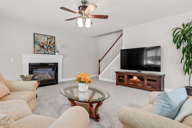 carpeted living room featuring stairs, a ceiling fan, a fireplace with flush hearth, and baseboards