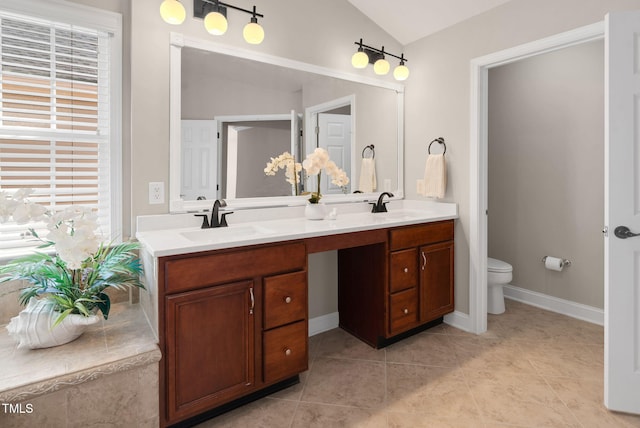 full bath with healthy amount of natural light, vaulted ceiling, toilet, double vanity, and tile patterned flooring