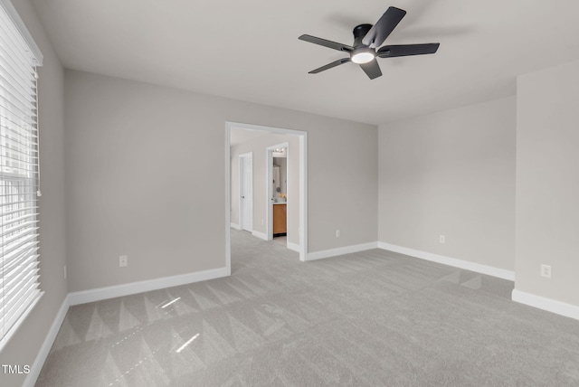 carpeted empty room featuring a ceiling fan and baseboards