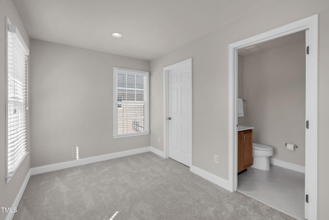 unfurnished bedroom with light colored carpet, baseboards, connected bathroom, and recessed lighting