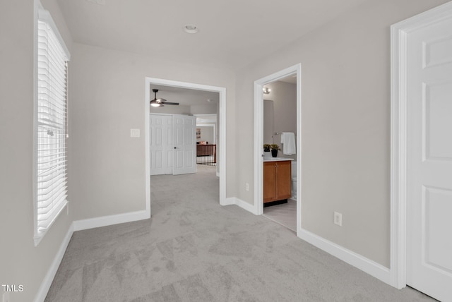 corridor featuring light carpet and baseboards