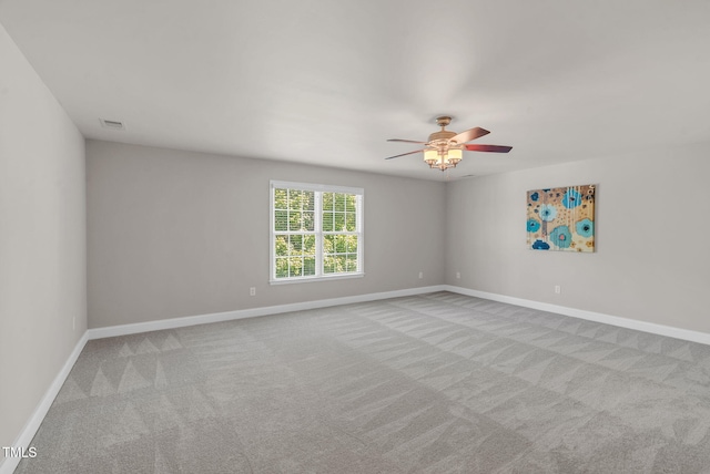carpeted spare room featuring baseboards and ceiling fan