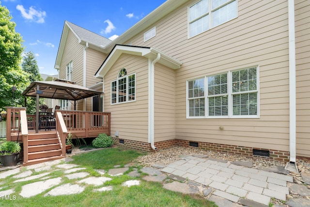 back of property featuring crawl space, a gazebo, a deck, and a patio