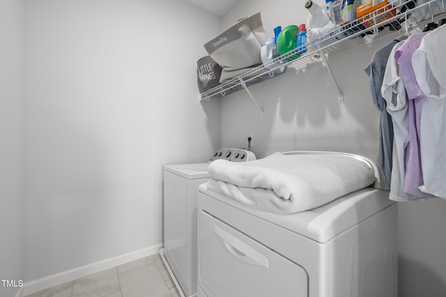 laundry room featuring baseboards, separate washer and dryer, and light tile patterned floors