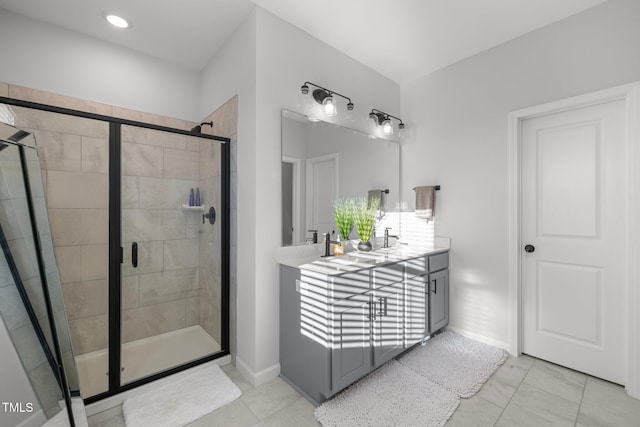 bathroom with a shower stall, double vanity, tile patterned flooring, and baseboards