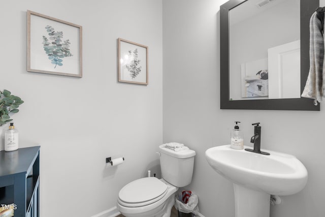 bathroom with toilet, a sink, and baseboards