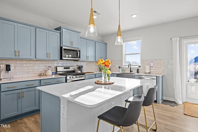 kitchen with appliances with stainless steel finishes, a sink, blue cabinets, healthy amount of natural light, and recessed lighting