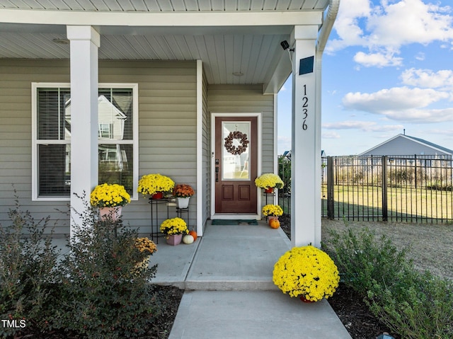 doorway to property with covered porch and fence